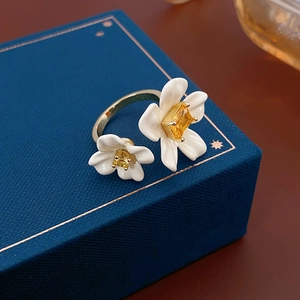 Close-up of gold plated flower ring with yellow gemstone on blue jewelry box