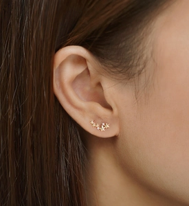 Close-up of golden star cluster earrings with small zircons worn on earlobe
