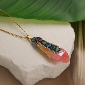 Detail shot of a pink crystal pendant with colorful rhinestones on a gold chain