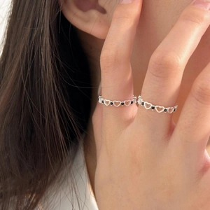Detail of 925 sterling silver hollow heart rings with black zircons on model fingers