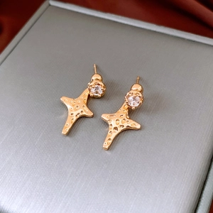 Detailed macro view of 18K gold plated star earrings with clear zircon stones on a jewelry box