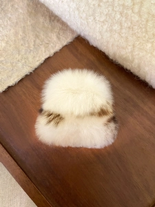 Gros plan d'une pince à cheveux en peluche blanche avec textures brunes sur bois