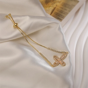 Detail of adjustable gold butterfly bracelet with crystal zircons on silk background