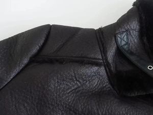 Detail of premium black faux leather and shearling texture on jacket collar and shoulder