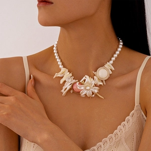Close-up of pearl necklace featuring resin flower and geometric shell charms on a model