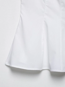Detailed close-up showing the hem stitching and cotton fabric texture of the white top