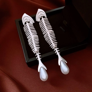 Macro detail of silver fishbone earrings with sparkling zircons and a pearl pendant drop