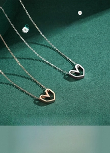 Close-up of minimalist hollow heart pendants in silver and rose gold finishes