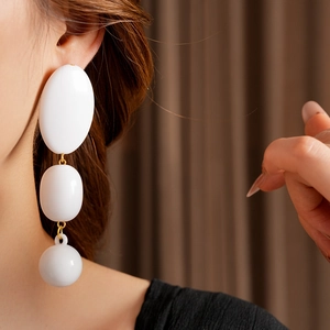 Close-up of elegant long white beaded tassel earrings worn by a model in soft lighting