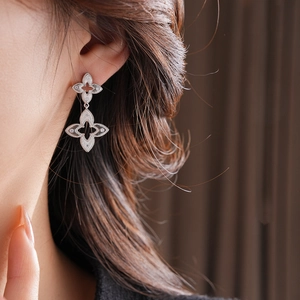 Macro view of silver floral earrings with brushed metal texture and sparkling gemstones