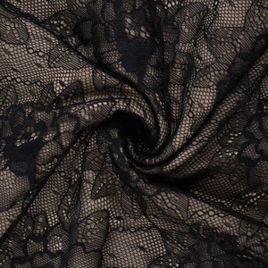 Gros plan sur un tissu de dentelle florale noire aux motifs complexes et drapé élégant