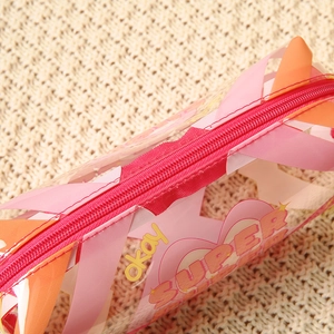 Transparent PVC toiletry bag with pink hearts and zipper on beige woven background