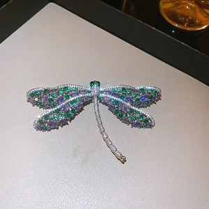 Detailopname van de libellebroche met blauw-paarse en groene edelstenen