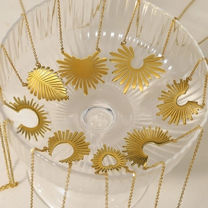 Collection of golden sunflower and leaf pendant necklaces arranged around a glass bowl