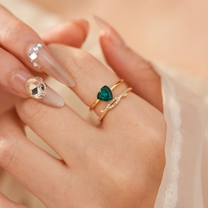 Détail d'un ensemble de bagues dorées avec pierre de zircon verte en forme de triangle