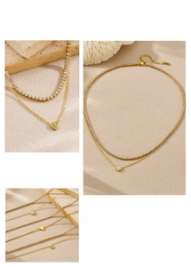 Close-up of double-layer gold necklace featuring heart pendant and cubic zirconia tennis chain