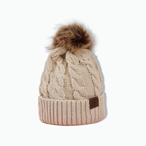 Detailed close-up of a beige knit beanie with a brown faux fur pom and leather logo patch