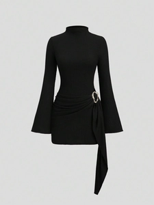 Détail du plissé à la taille avec anneau doré sur une robe moulante noire à manches longues