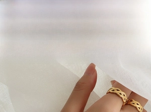 Detail of gold woven cutout rings layered on finger with minimalist hollow design