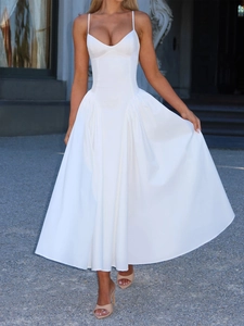 Elegant white spaghetti strap maxi dress with a flared skirt against a classical background