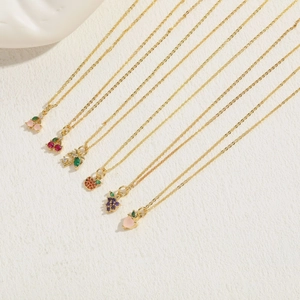 Macro shot of 14K gold plated necklaces featuring zircon fruit pendants like cherry and peach