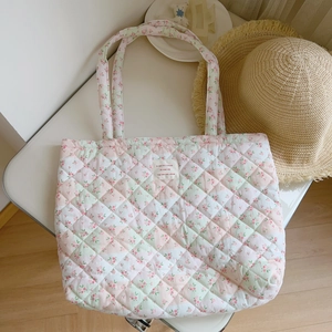 Macro view of floral quilted cotton tote bag with vintage french script fabric patch