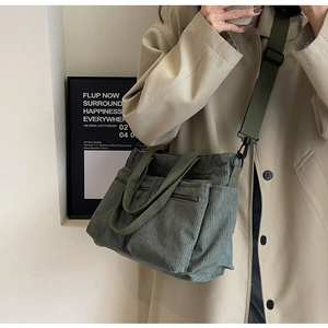 Detail of green corduroy crossbody bag with adjustable wide strap shown on a model