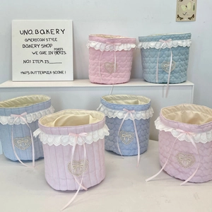 Close-up of quilted fabric storage baskets with lace trim and ribbon bows for desk organizing