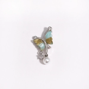 Macro detail of asymmetric butterfly pendant with enamel wings, zircon and a pearl
