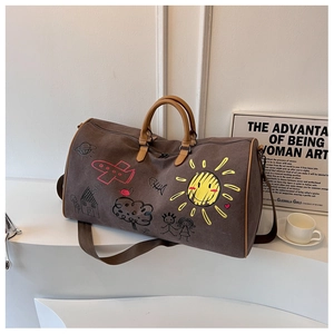 Detail of a dark brown travel bag with colorful hand-drawn graffiti and PU leather handles