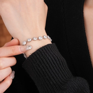 Close-up of heart-shaped zircon bracelet on wrist with silver-toned sparkling stones