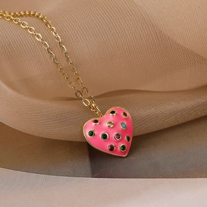 Macro detail of gold plated heart pendant with pink enamel and colorful zircon stones