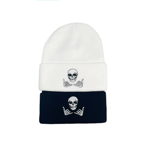 Black and white knit beanies with skull and bone hand embroidery in a classic cuffed style