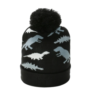 Detailed texture of kids knit beanie with dinosaur pattern and black faux fur pom-pom