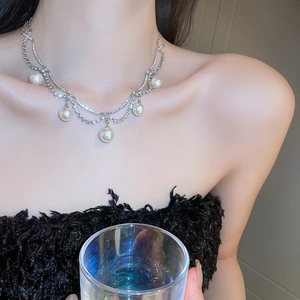 Detail of double-layer necklace with five white pearls and shimmering crystal chain