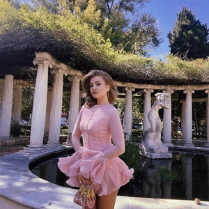 Pink long sleeve flare dress with pearl buttons and layered ruffles in garden setting