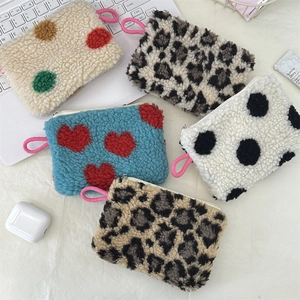 Flat lay of colorful plush heart and leopard print mini cosmetic bags on a white desk