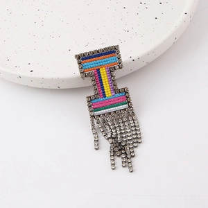 Detailed view of colorful woven brooch featuring hanging rhinestone fringes on ceramic