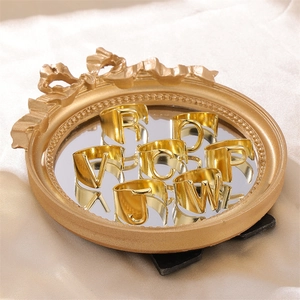 Retro golden initial open rings with English letters displayed on a vintage mirror