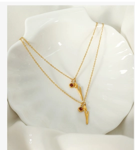 Detail of 18k gold plated tulip and ruby red stone pendants on a shell plate