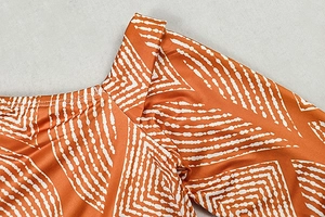 Detail of orange satin fabric with white wave print on shoulder and neckline