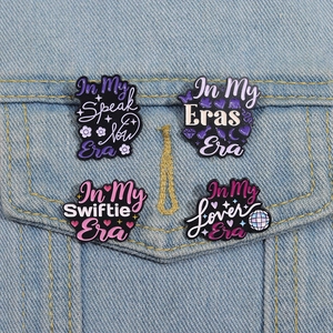 Enamel Taylor Swift badges pinned to denim jacket, showcasing Speak Now and Lover designs