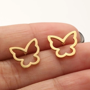 Detailed view of a gold hollow butterfly stud earring held on a finger for size reference