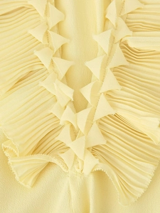 Detailed macro view of yellow pleated chiffon fabric with layered ruffle decorative edges