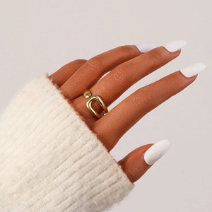 Detail of a minimalist gold-plated U-shaped ring with a bead on a model finger