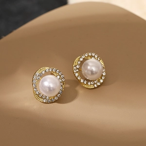 Detailed close-up of golden spiral earrings with elegant pearls and clear rhinestones