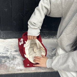 Detailed view of red felt tote bag with white flower decor and smooth zipper closure