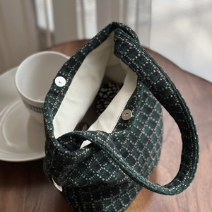 Green plaid tweed mini handbag with magnetic closure on a wooden table setup