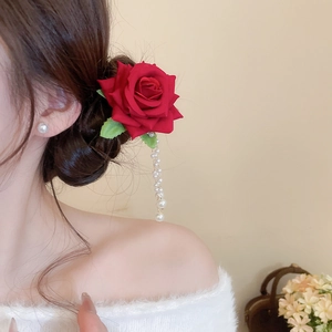 Detail of red rose hair clip with long pearl tassels styled on a model's hair bun