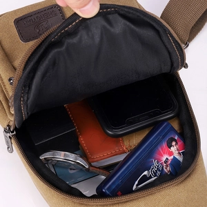 Khaki canvas crossbody chest bag showing spacious main compartment with multiple items